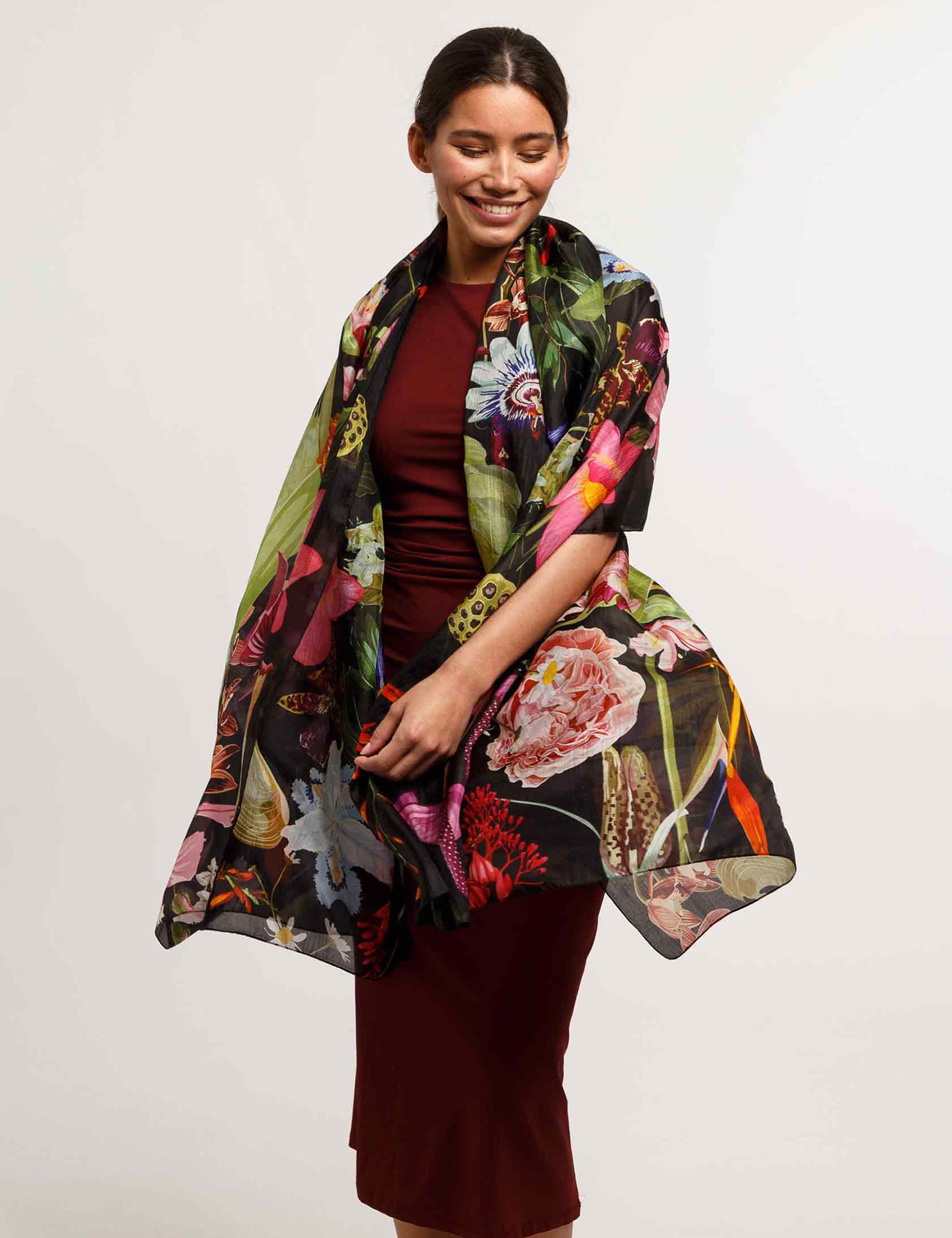 Woman wearing a colorful floral scarf on a plain background