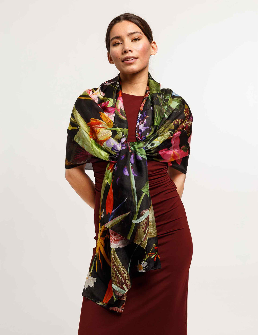 Woman wearing a colorful floral scarf on a plain background